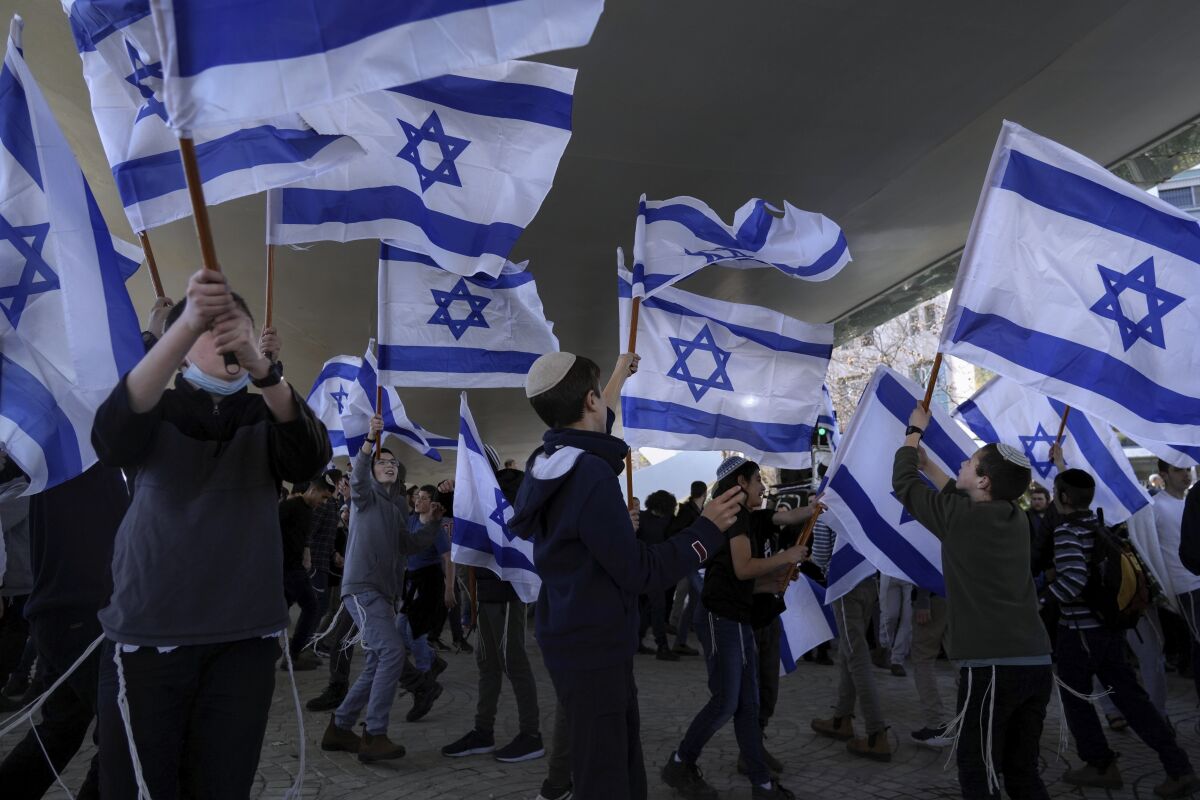 Religious Jewish youth wave Israeli flags during a protest against religious reforms, in Jerusalem, Sunday, Jan. 30, 2022. Israel’s new government has taken aim at the country’s powerful religious establishment with a pair of reforms that would chip away at the tight grip of the country's chief rabbinate on many aspects of daily life. (AP Photo/Mahmoud Illean)