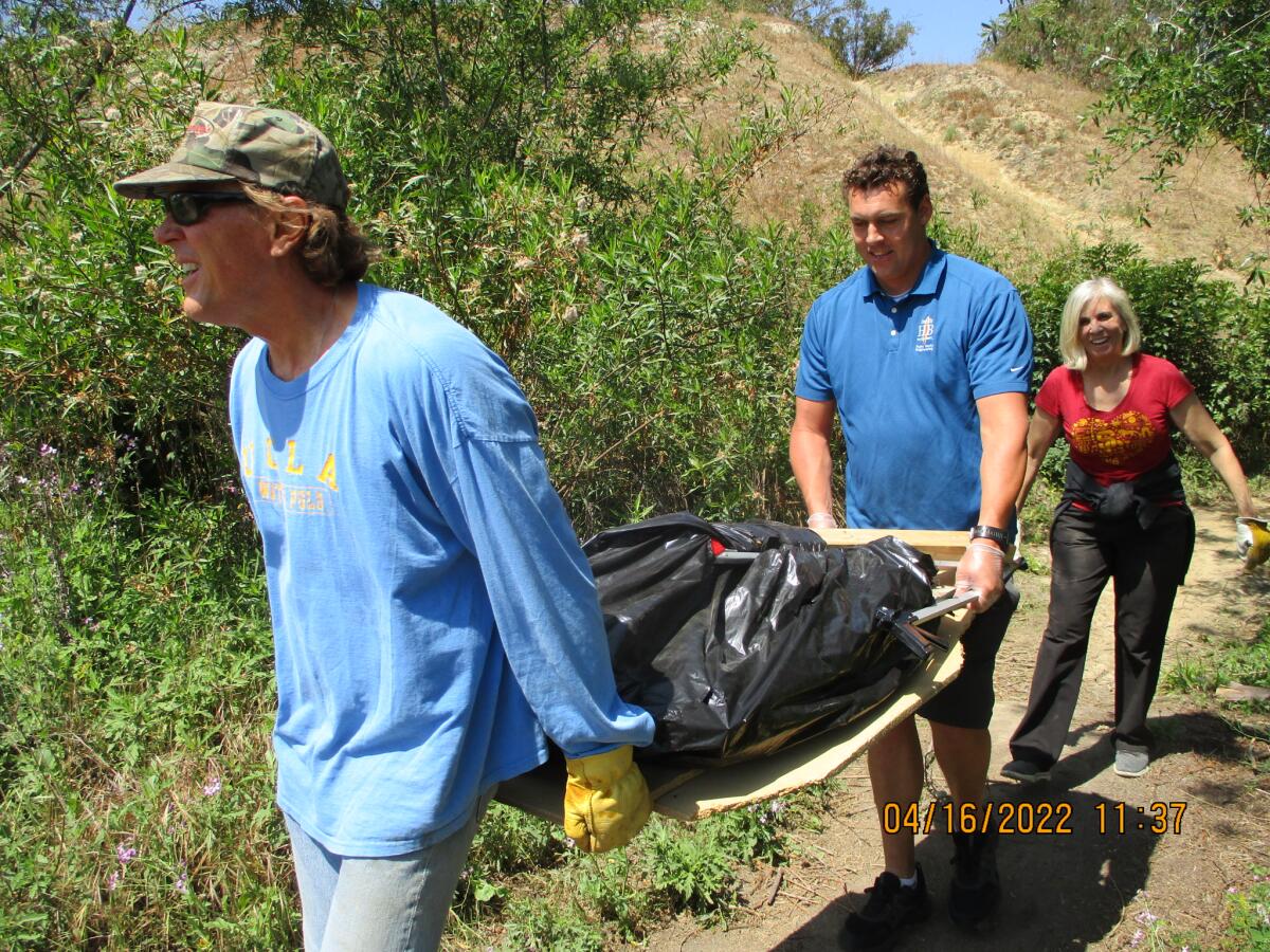 Volunteers haul trash out of Bartlett Park in Huntington Beach.