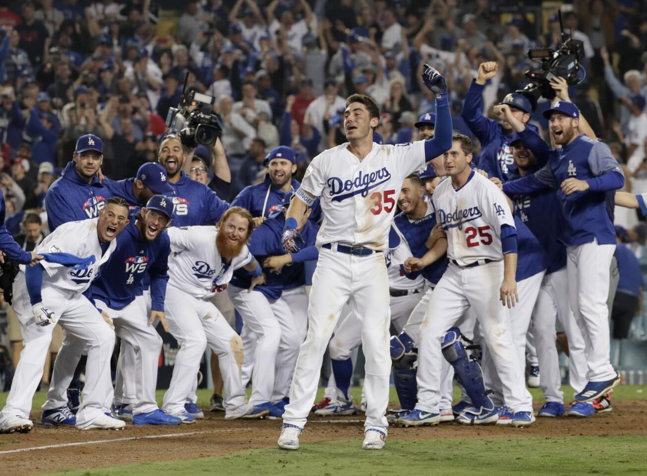 Dodger players including Cody Bellinger wait to greet Max Muncy after hitting the game-winning homerun in the 18th inning against the Red Sox.