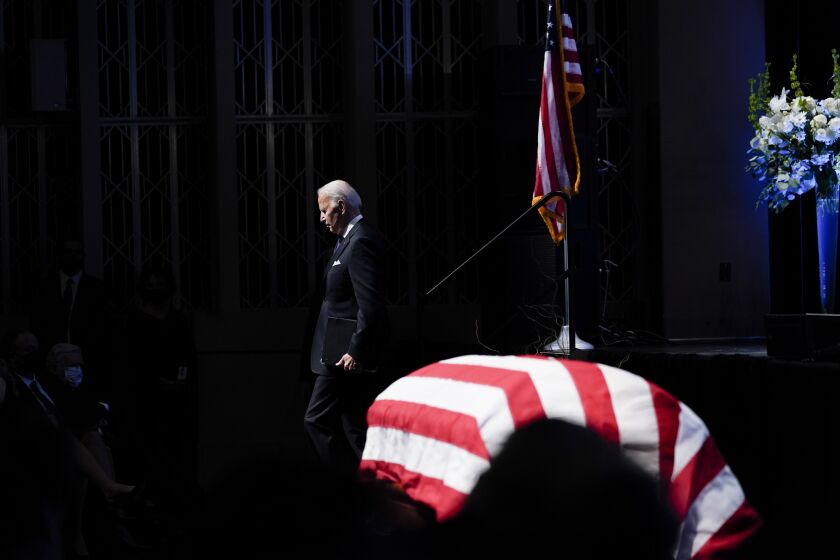President Joe Biden walks by the flag-draped casket of former Senate Majority Leader Harry Reid after speaking during a memorial service for Reid at the Smith Center in Las Vegas, Saturday, Jan. 8, 2022. (AP Photo/Susan Walsh)