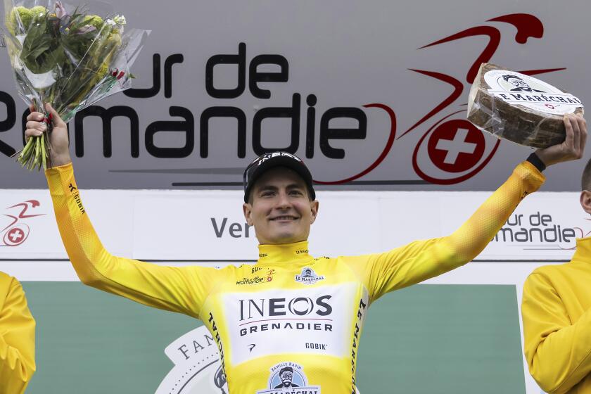 The winner of the Tour de Romandie, Carlos Rodriguez, right, from Spain of team Ineos Grenadier, celebrates on the podium after the fifth and final stage, a 150,8 km race between Vernier and Vernier at the 77th Tour de Romandie UCI World Tour Cycling race, in Vernier near Geneva, Switzerland, Sunday, April 28, 2024. (Jean-Christophe Bott/Keystone via AP)