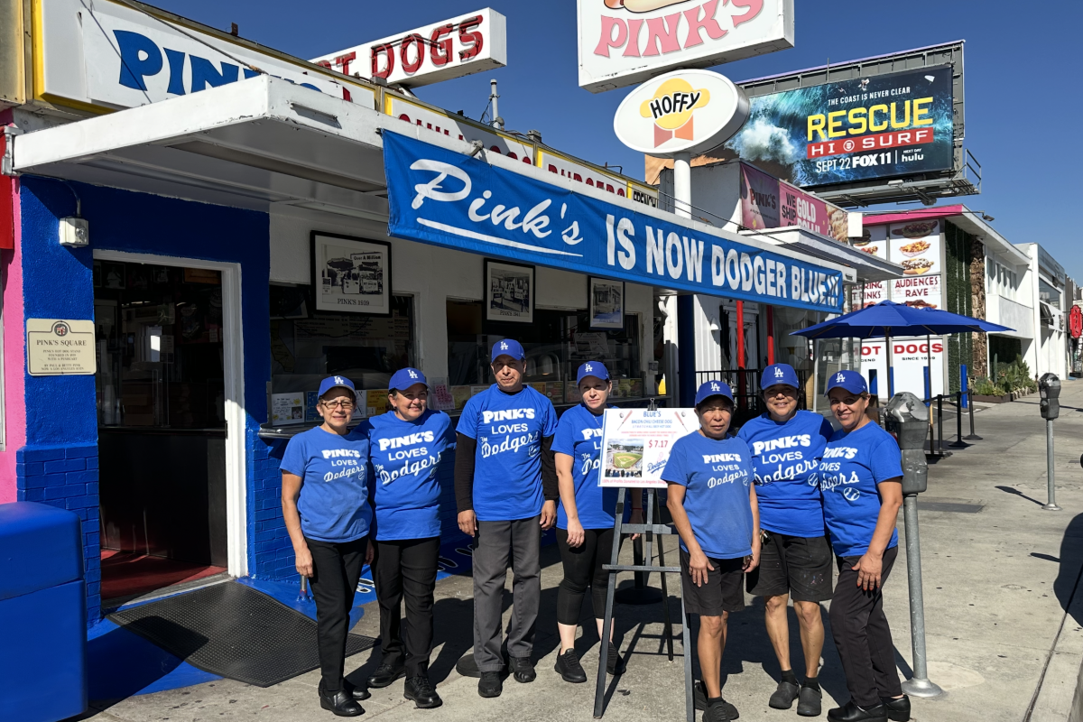 An exterior of Pink's in Hollywood, painted blue, with staff in blue Pink's shirts standing out front.