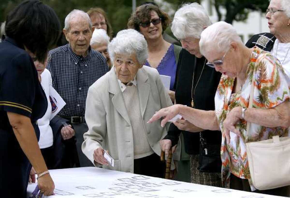 Sister Mary Jean ferry, class of '52 and 78 years old, at center with name tag in hand, checks in at the Holy Family High School 75th Anniversary Celebration on school grounds in Glendale.