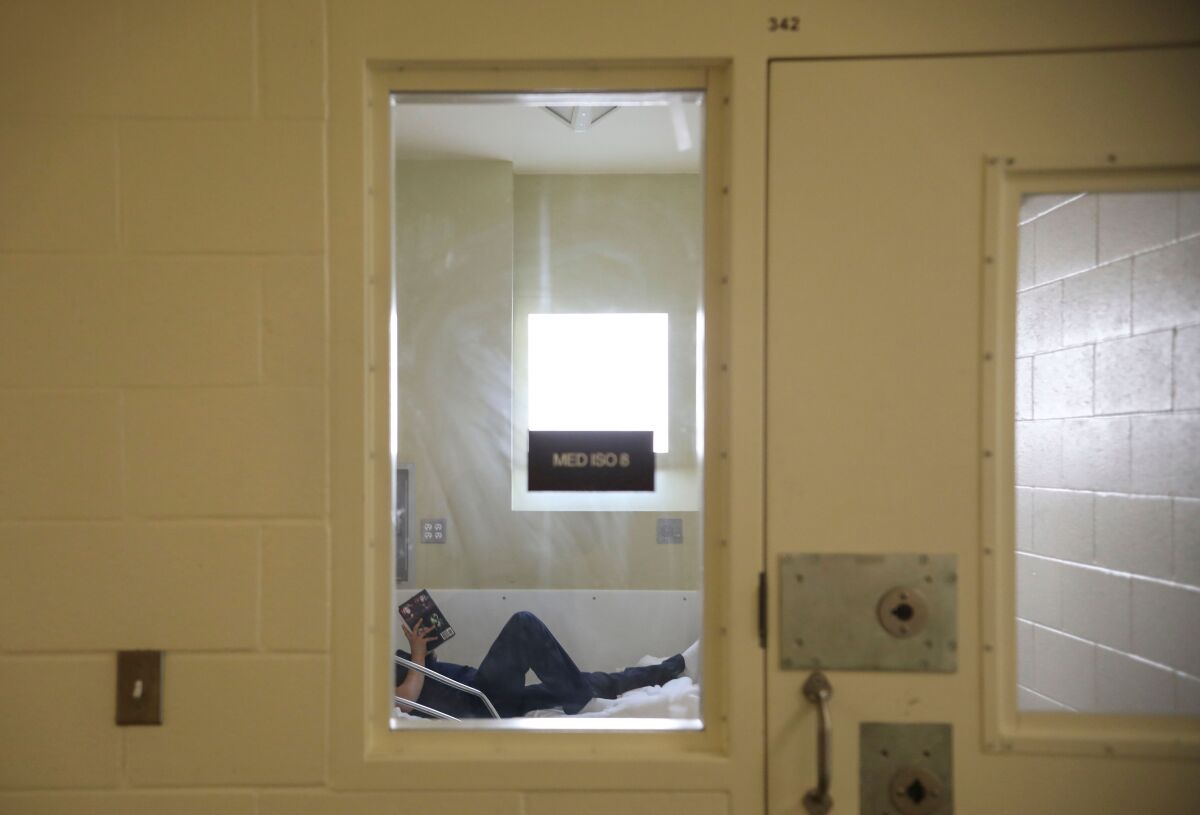 An inmate reads a book while in the infirmary at Las Colinas Detention and Reentry Facility