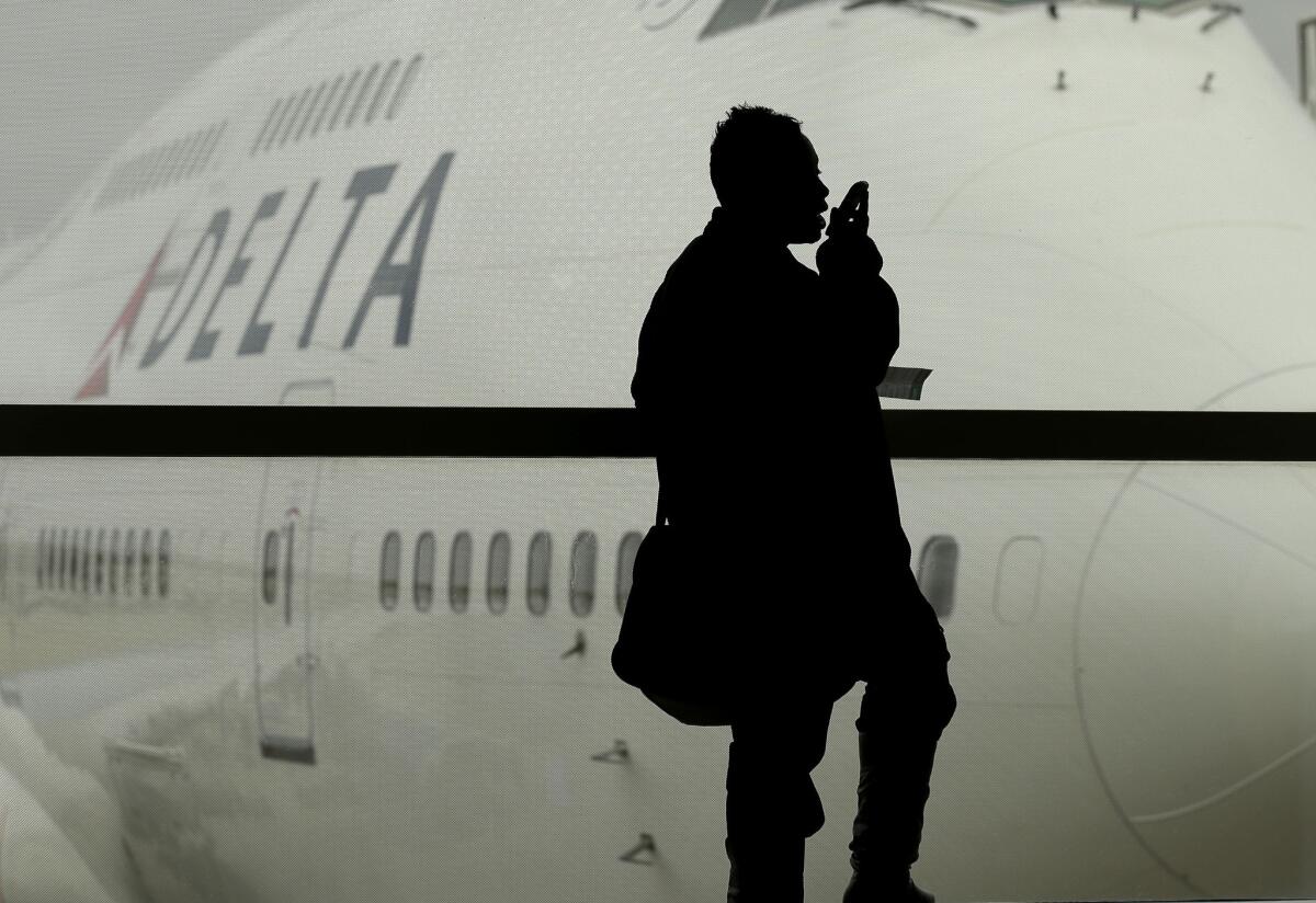 A traveler on Delta Air Lines waits for her flight in Detroit. The carrier has announced plans to install satellite-based wireless internet on many long-haul flights.