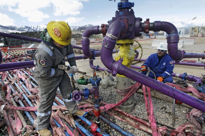 Workers tend to a well head during a hydraulic fracturing operation outside Rifle, Colo.