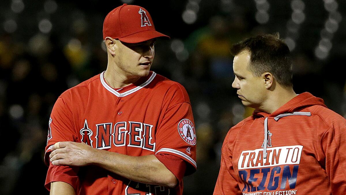 Angels pitcher Garrett Richards, left, leaves the field with a trainer during the fifth inning against the Oakland Athletics on April 5.