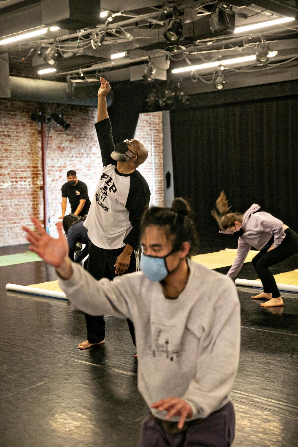 A dancer gestures in a rehearsal studio.