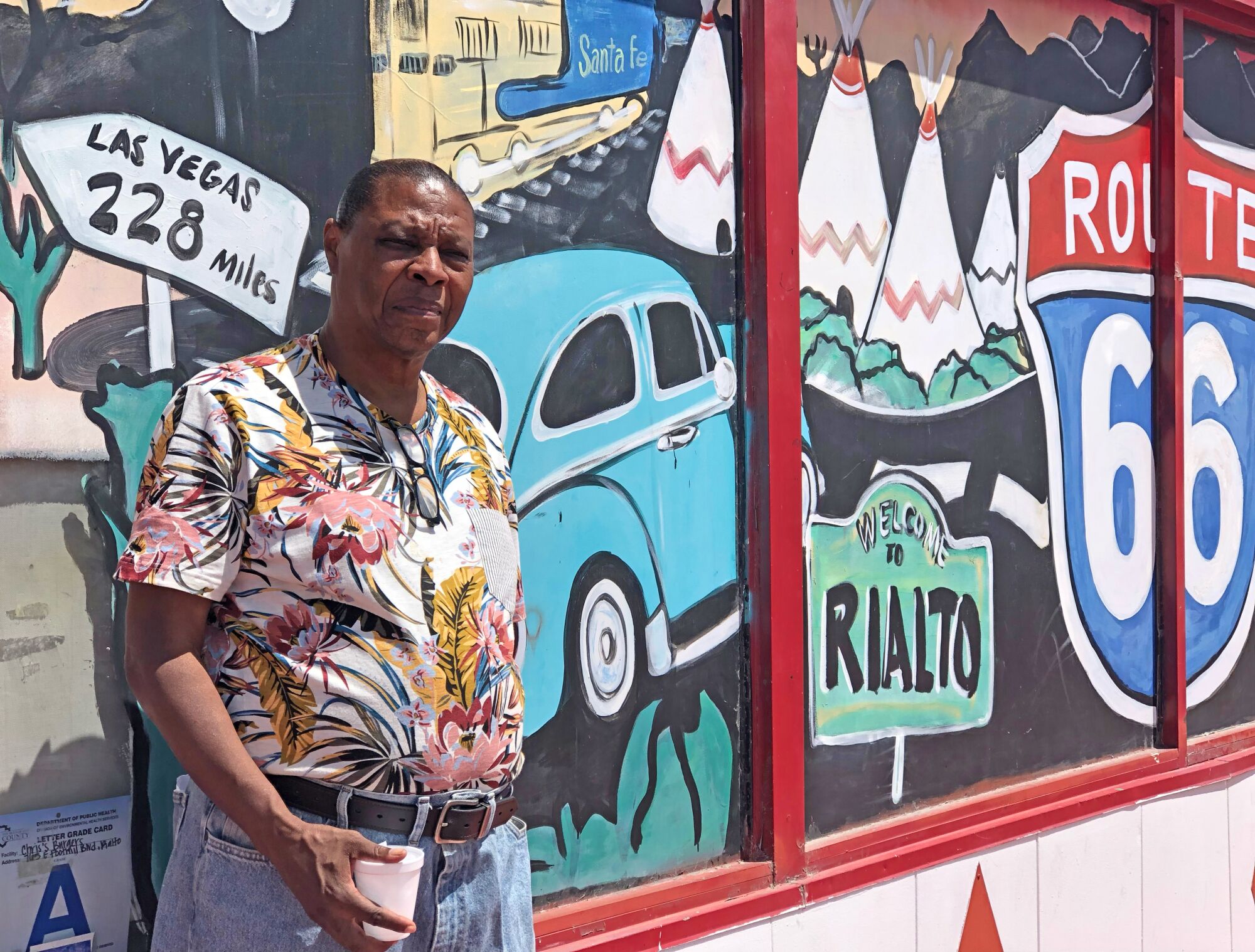 A man standing next to a mural of Route 66's heyday