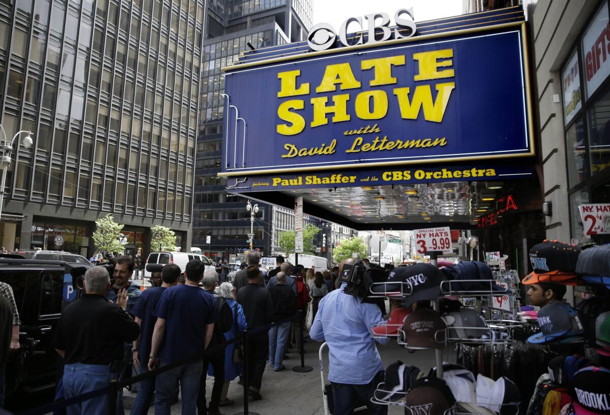 People gather under the marquee of the Ed Sullivan Theater in New York, Wednesday, May 20, 2015. After 33 years and 6,028 broadcasts of his late-night show, David Letterman is retiring.