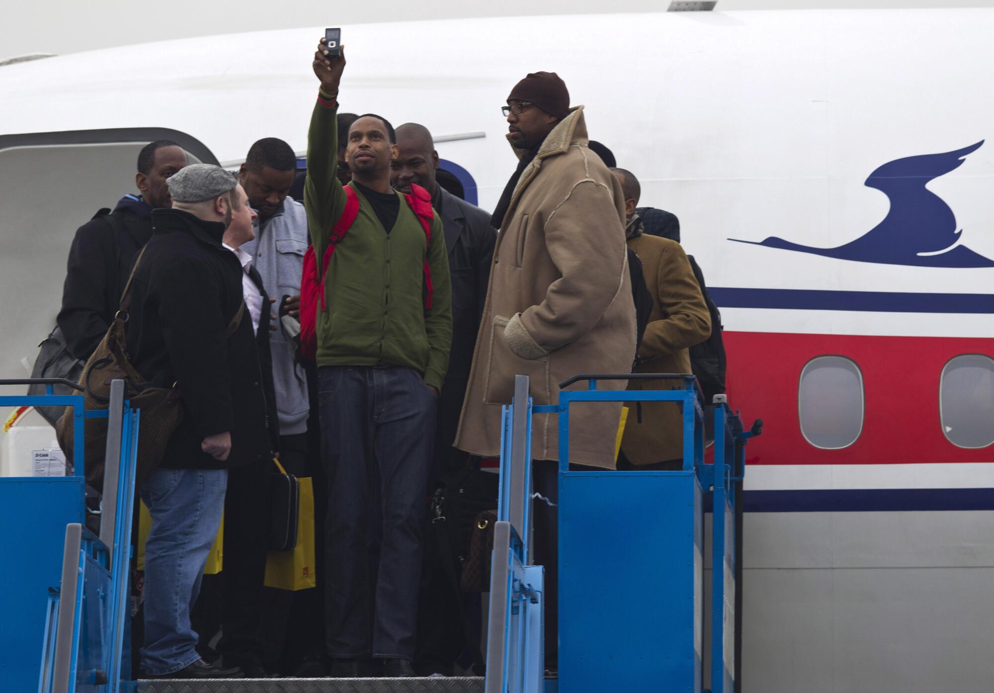 Vin Baker, right, waits as Jerry Dupree, center, takes photos after their arrival in North Korea with Dennis Rodman.