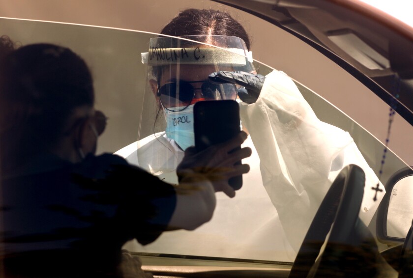 Medical personnel collect samples for COVID-19 tests at a drive-up site in Cardiff, Calif.