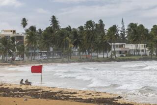 Tourists sit on La Pared beach as Tropical Storm Ernesto passes by Luquillo, Puerto Rico, Tuesday, Aug. 13, 2024. (AP Photo/Alejandro Granadillo)