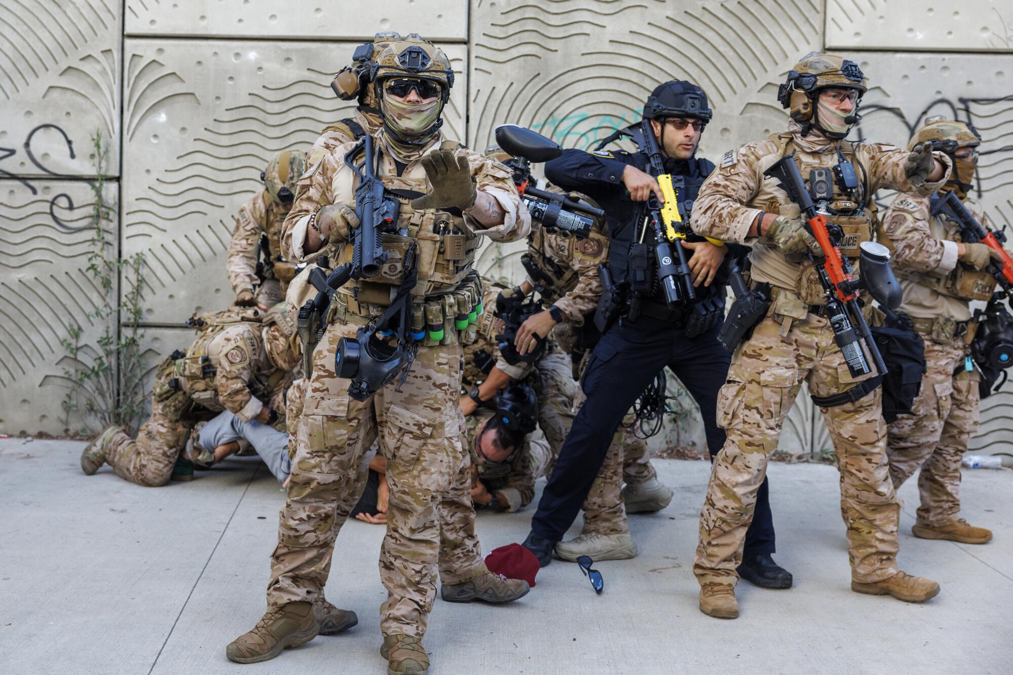 soldiers in tactical gear detain a protester