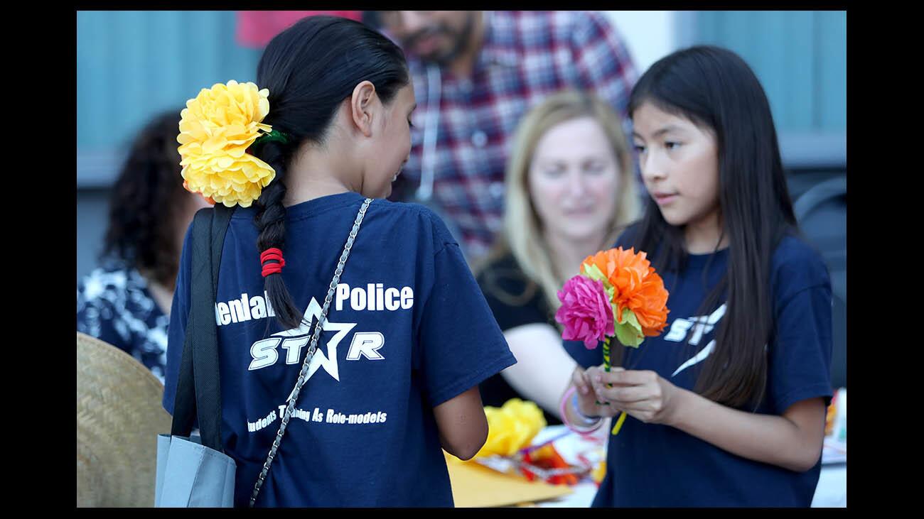 Wearing paper flowers she made by hand, Jocelyn Banuelos, 10 from Glendale, left, looks over at how her friend Karen Luna's flowers turned out during National Night Out at Pacific Park in Glendale on Tuesday, Aug. 7, 2018. The city held similar events in about two dozen places throughout Glendale.