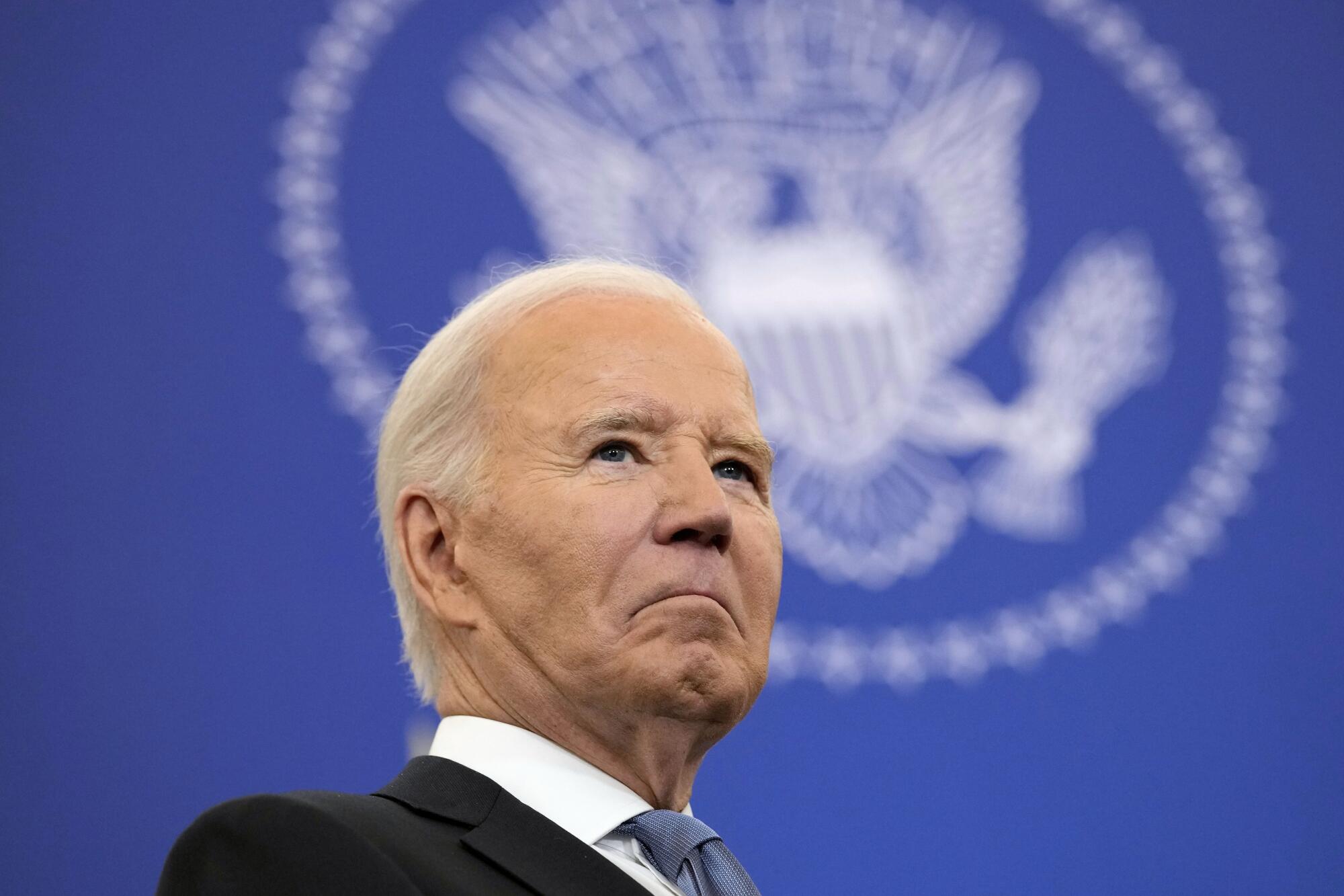 President Biden frowns with the U.S. seal in the background