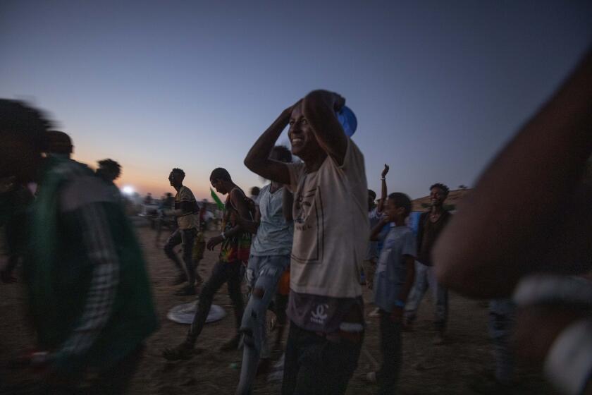 Tigray men who fled the conflict in Ethiopia's Tigray region, run to recieve cooked rice from charity organization Muslim Aid, at Umm Rakouba refugee camp in Qadarif, eastern Sudan, Friday, Nov. 27, 2020. Ethiopian Prime Minister Abiy Ahmed again ruled out dialogue with the leaders of the defiant Tigray region Friday but said he was willing to speak to representatives "operating legally" there during a meeting with three African Union special envoys trying to end the deadly conflict between federal troops and the region's forces. (AP Photo/Nariman El-Mofty)