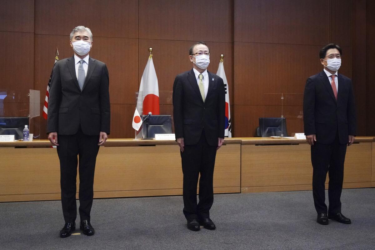 Three men stand straight.
