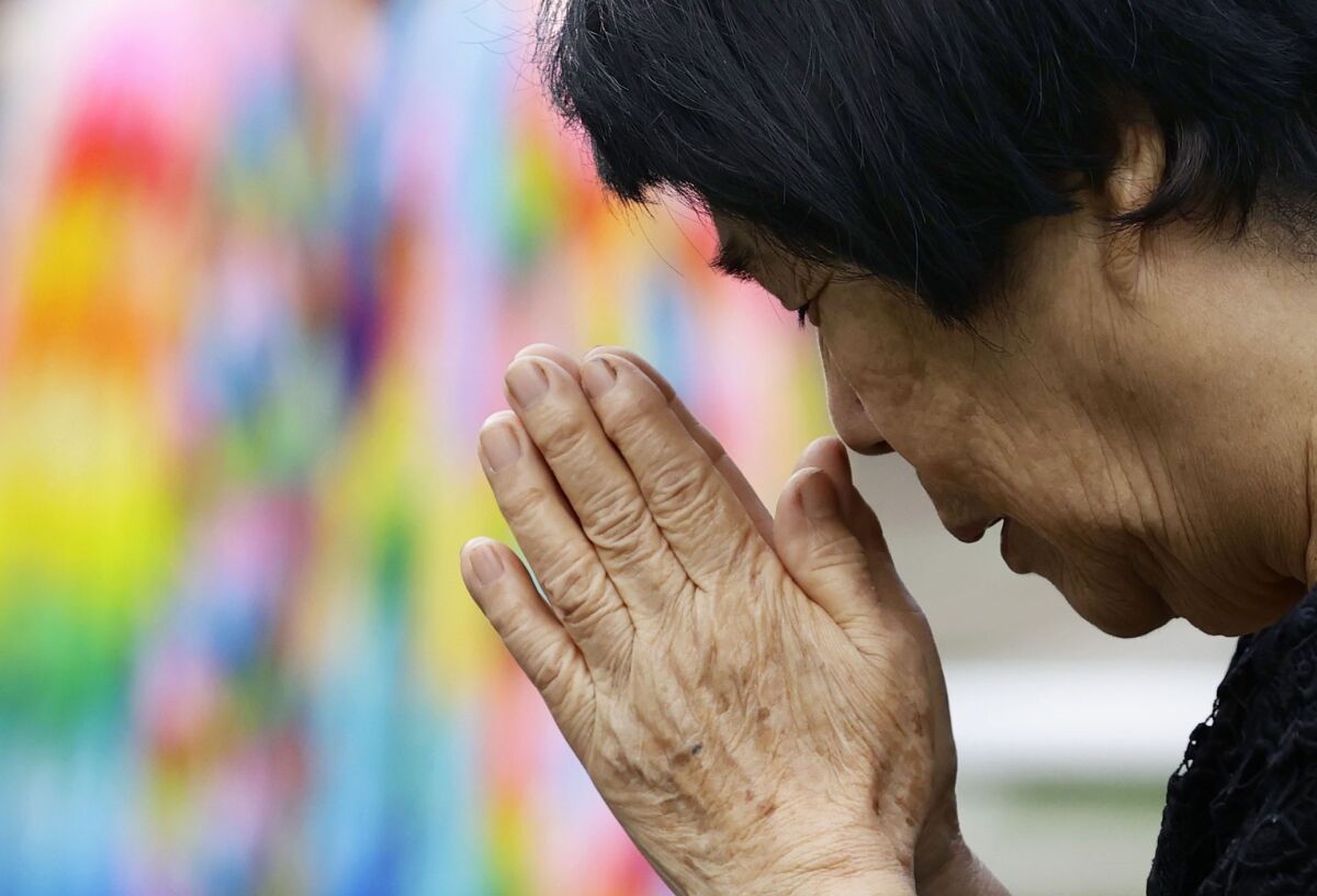 A bereaved family member prays for the victims of U.S. atomic bombing at the Atomic Bomb Hypocenter Park in Nagasaki, southern Japan, Sunday, Aug. 9, 2020. Nagasaki marked the 75th anniversary of the atomic bombing on Sunday. (Kyodo News via AP)