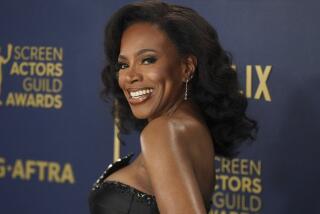 Sheryl Lee Ralph in a black sleeveless gown turning her shoulder to the camer and smiling against a dark blue background