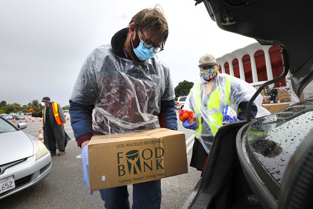 Union members Jacob De Wilde, left, and Lesli Lytle on Friday loaded a car with food for people struggling from the impact of coronavirus closings.