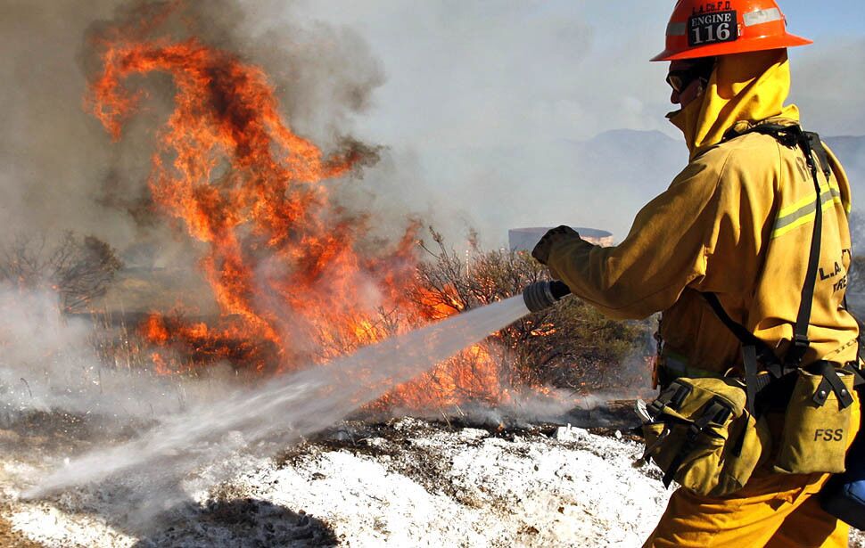 Firefighters battle hot spots from the Springs fire in the mountains above Malibu.