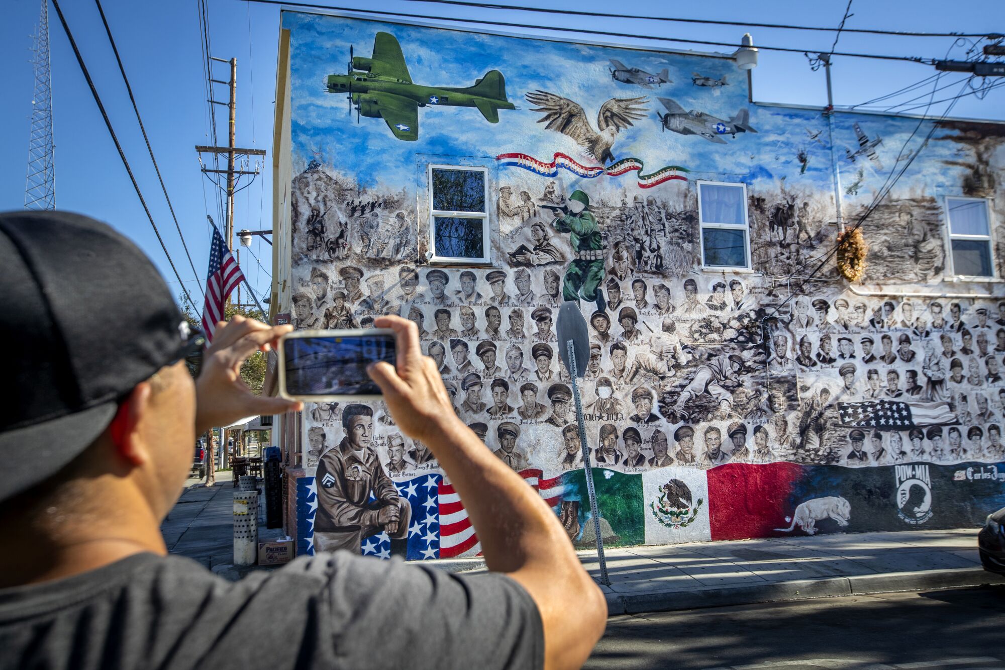 Tommy Cota takes photos of the "Among Heroes" veterans memorial mural outside La Chiquita Grocery in Santa Ana.