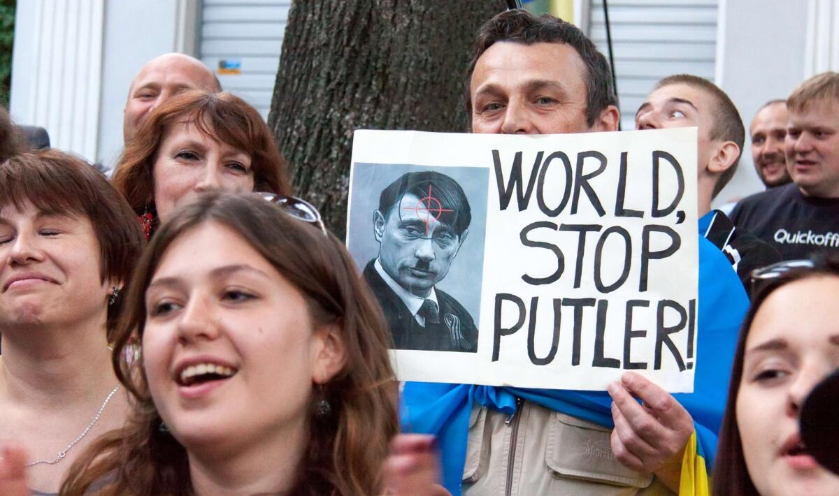 A man holds a placard depicting Russia's president Vladimir Putin as Hitler during a protest against Russia's president in front of the Russian consulate in the northeastern Ukrainian city of Kharkiv. PEN International has joined the voices condemning Russia's action in Ukraine.