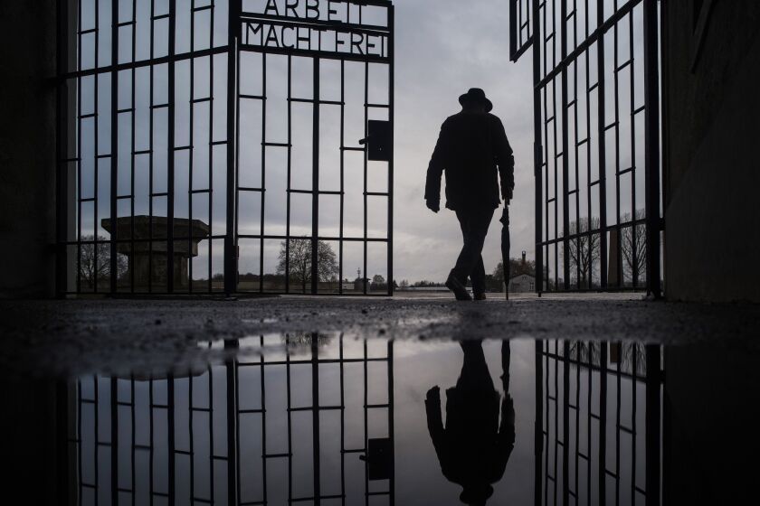 File - In this Sunday, Jan. 27, 2019 file photo, a man walks through the gate of the Sachsenhausen Nazi death camp with the phrase 'Arbeit macht frei' (work sets you free) during International Holocaust Remembrance Day in Oranienburg, about 30 kilometers (18 miles), north of Berlin, Germany. Hundreds of Holocaust survivors in Austria and Slovakia are getting vaccinated against the coronavirus exactly 76 years after the liberation of the Nazi's Auschwitz death camp. More than 400 Austrian survivors were invited to get the vaccine at Vienna's biggest mass vaccination center on International Holocaust Remembrance Day on Wednesday Jan. 27, 2021. (AP Photo/Markus Schreiber, file)