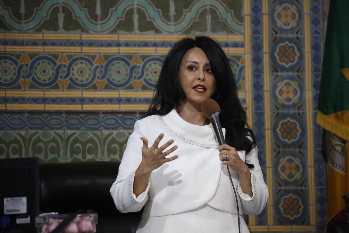 A woman wearing all white speaks while holding a microphone