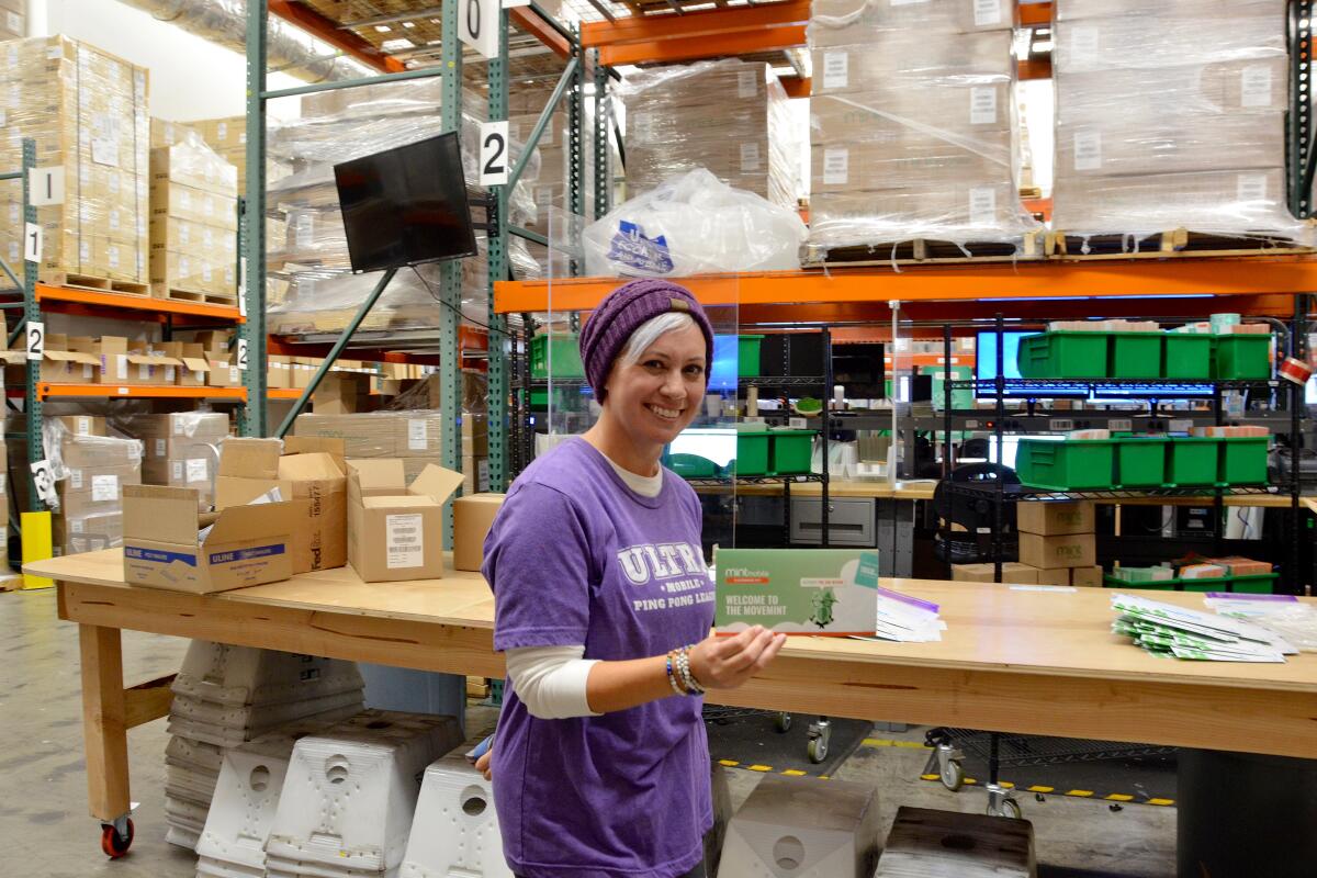 Stacy Morris, director of employee sxperience holds a Mint Mobile SIM kit inside the supply chain center in Costa Mesa.