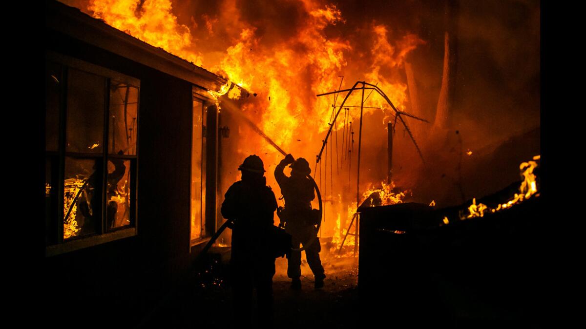 Firefighters scramble to try to control a house aflame after a wildfire swept through a county road near Seigler Springs, Calif., on Sunday night.