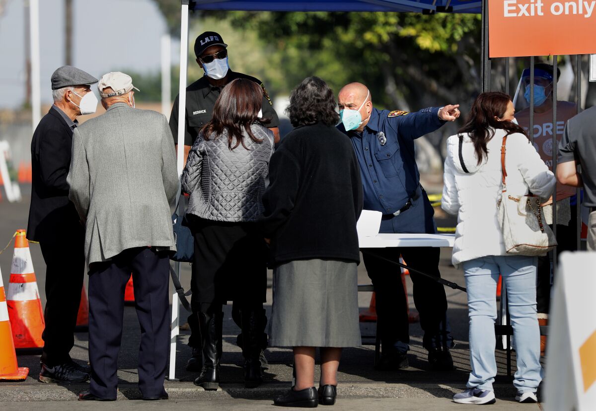 People line up at a checkpoint to be vaccinated at W. 79th Street and S. Mariposa Avenue in South Los Angeles on Tuesday. 