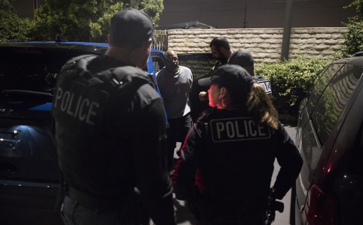ICE agents surround a man at night.