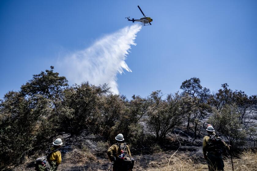 BEAUMONT, CA - JULY 16, 2023: Fire crews get help from a water dropping helicopter while putting out hotspots near Bolo Court at the Rabbit fire on July 16, 2023 in Beaumont, CA. (Gina Ferazzi / Los Angeles Times)