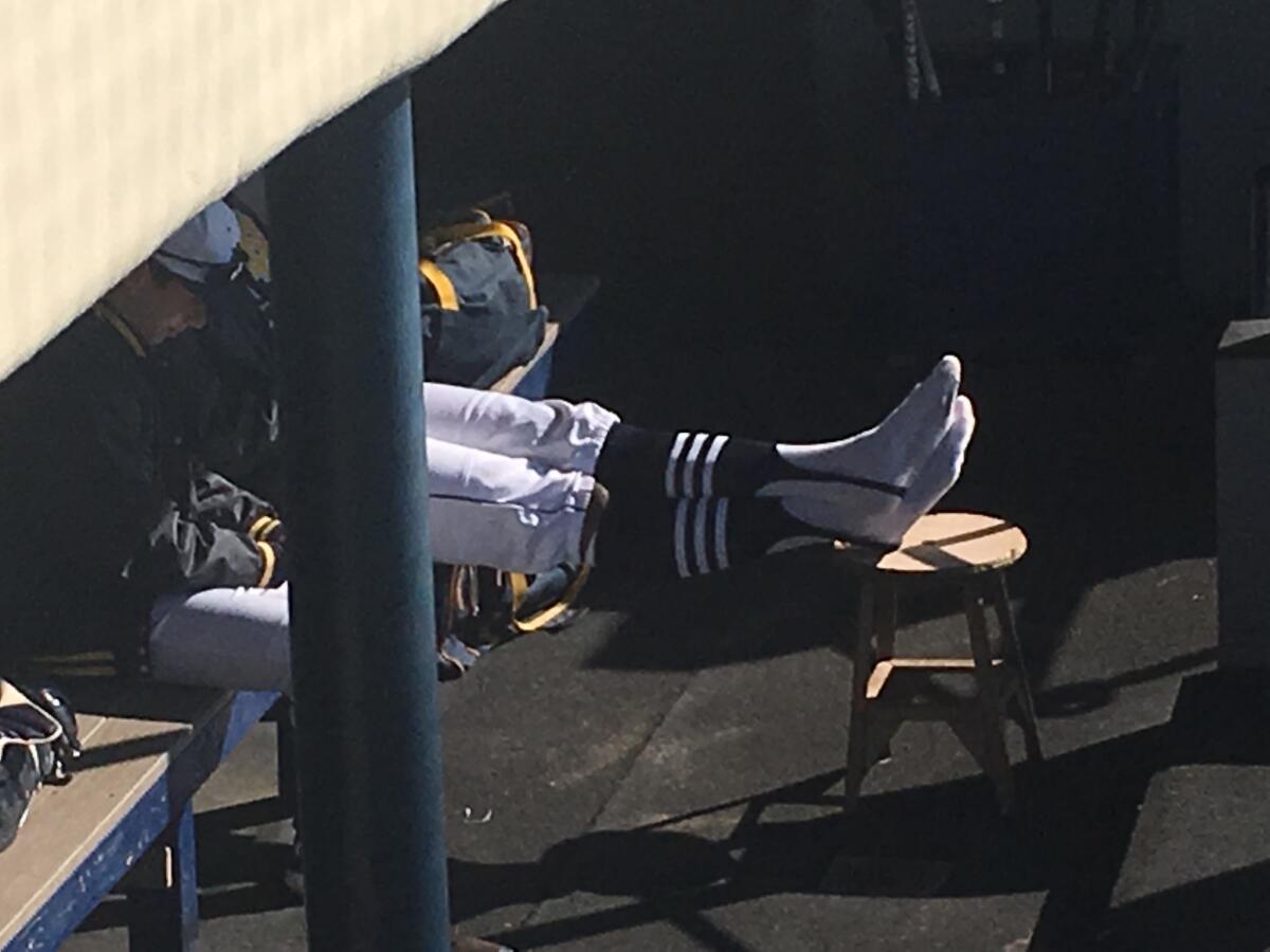 In preparing for his season debut on Saturday, Hunter Greene of Sherman Oaks Notre Dame takes a moment to relax in the dugout, cleats off. He hit grand slam in win over Rio Mesa.