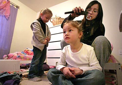 Audrey Delgadillo, 20, helps get her sisters Ashley, 4, right, and Emily 3, ready for day care. Delgadillo's mother and stepfather, Sgt. Claudia Hernandez-Smith and Sgt. Gary Smith, are serving in Iraq. Their departure nearly eight months ago left Delgadillo to look after her four sisters until they return.