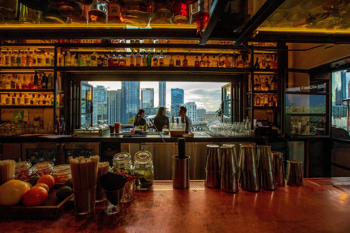 A bar interior with a window view of the downtown L.A. skyline