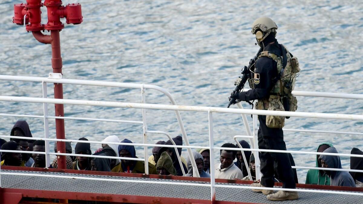 A Maltese special operations soldier stands guard over a group of migrants on a tanker that had been hijacked.