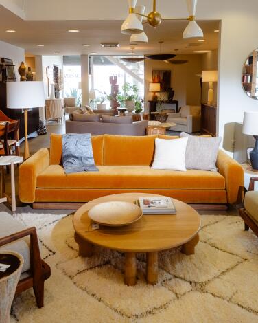 A rust-colored velvet sofa is decorated with a throw blanket and pillows at Lawson Fenning. 