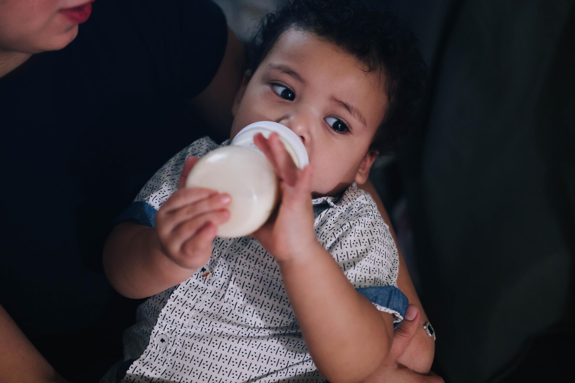 A baby drinks from a bottle.