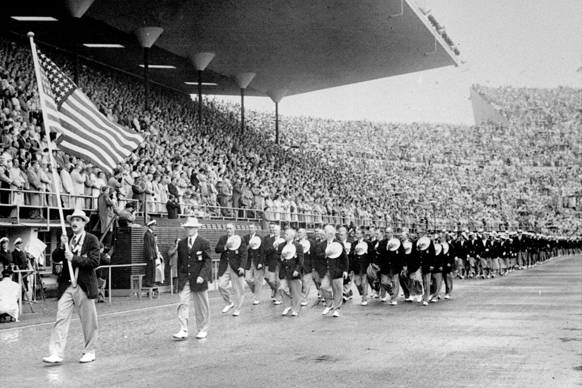 FILE - In this July 21, 1952, file photo, members of the United States Olympic team holding their hats over their hearts as they pay tribute to Finland's President Juho K. Passikivi, march into Olympic Stadium during the opening ceremonies of the Summer Olympic games in Helsinki, Finland. (United Press via AP, File)