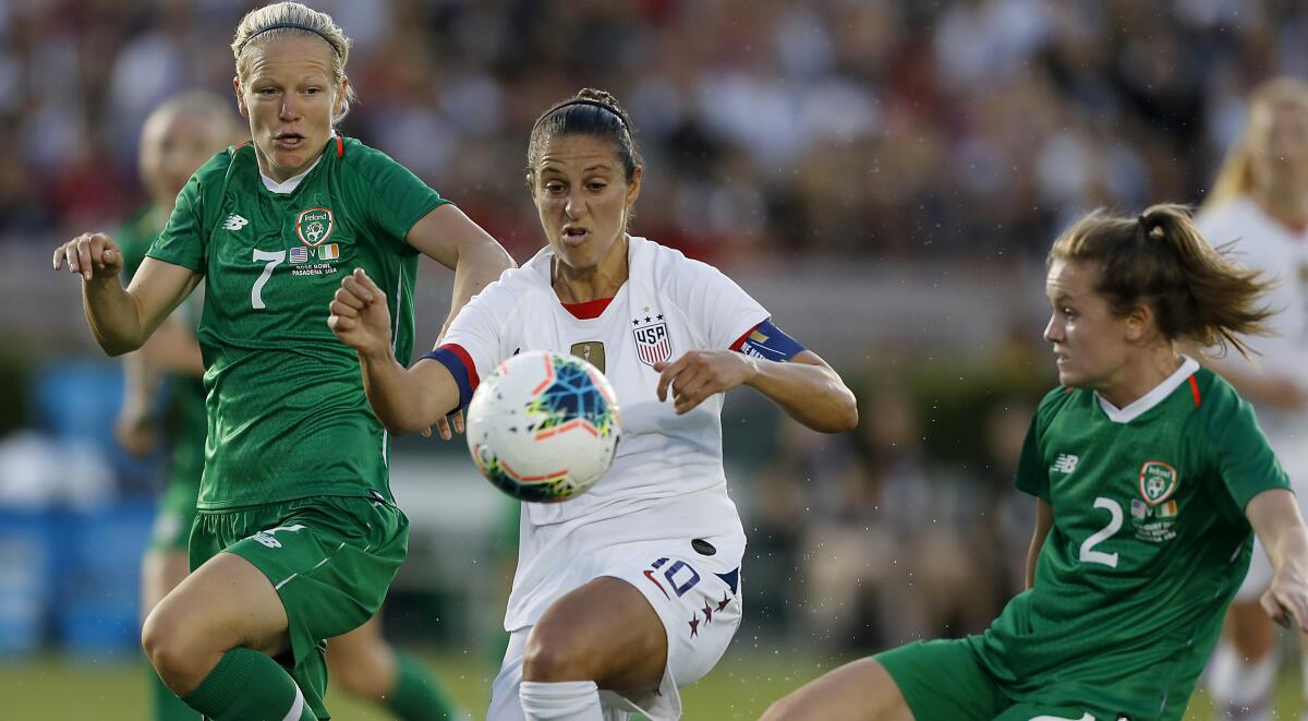 U.S. forward Carli Lloyd tries to control the ball between Ireland's Diane Caldwell, left, and Heather Payne.