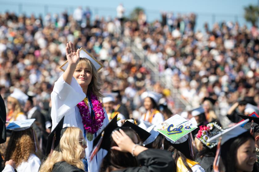 A senior waves to loved ones in the stands during her graduation ceremony at Huntington Beach High on Wednesday.