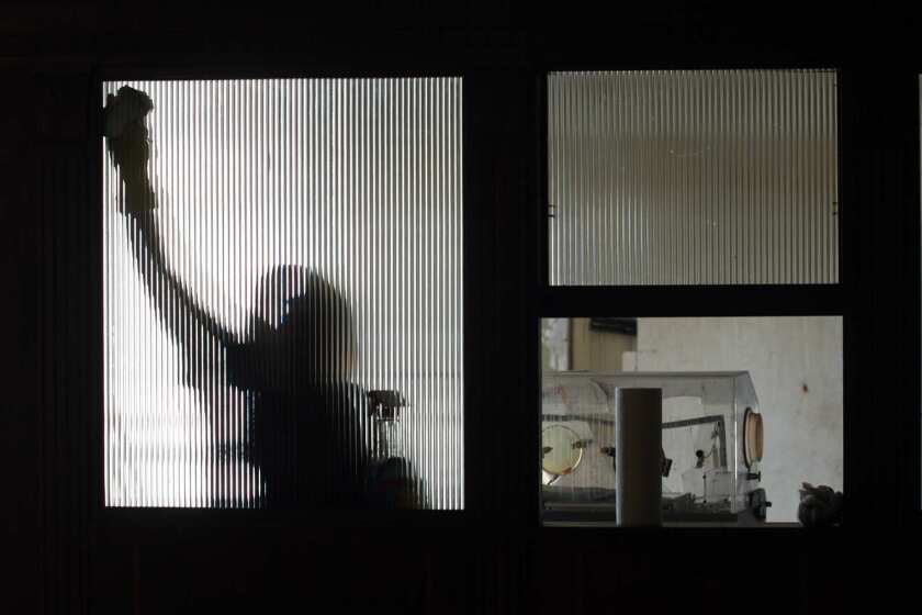 A maintenance worker cleans a window inside the former Linda Vista Community Hospital in Boyle Heights. The site, which some say is haunted, is set to be converted into apartments for low-income seniors. The incubator at right is left over from a film shoot.