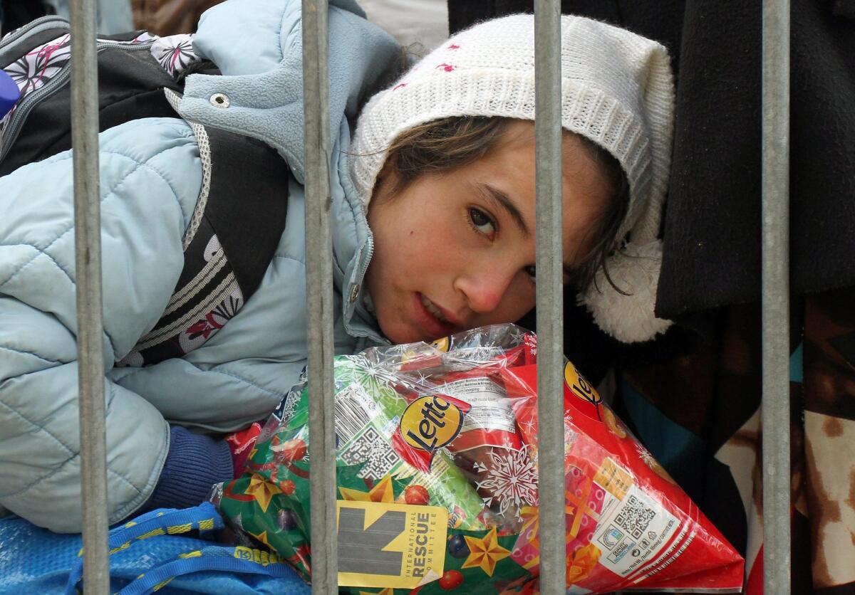 A girl from Syria rests on a bag of humanitarian aid while waiting to be registered at a registration camp in the city of Presevo, Serbia, in December 2015.