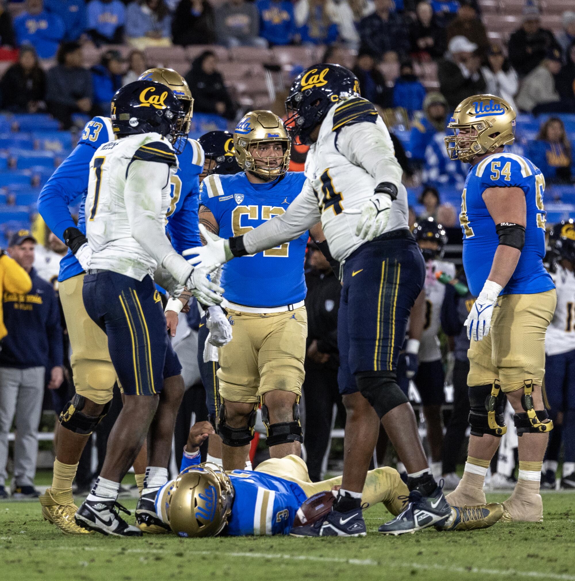 Cal's David Reese gets hand slap from Xavier Carlton after sacking UCLA quarterback Dante Moore, who is on the ground