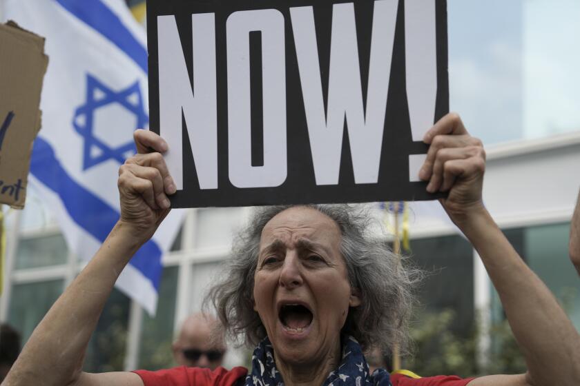 A woman holds a banner and shouts slogans with families and supporters of Israeli hostages held by Hamas in Gaza during a protest calling for their return, outside a meeting between U.S. Secretary of State Antony Blinken and families of hostages in Tel Aviv, Israel, Wednesday, May 1, 2024. (AP Photo/Oded Balilty)