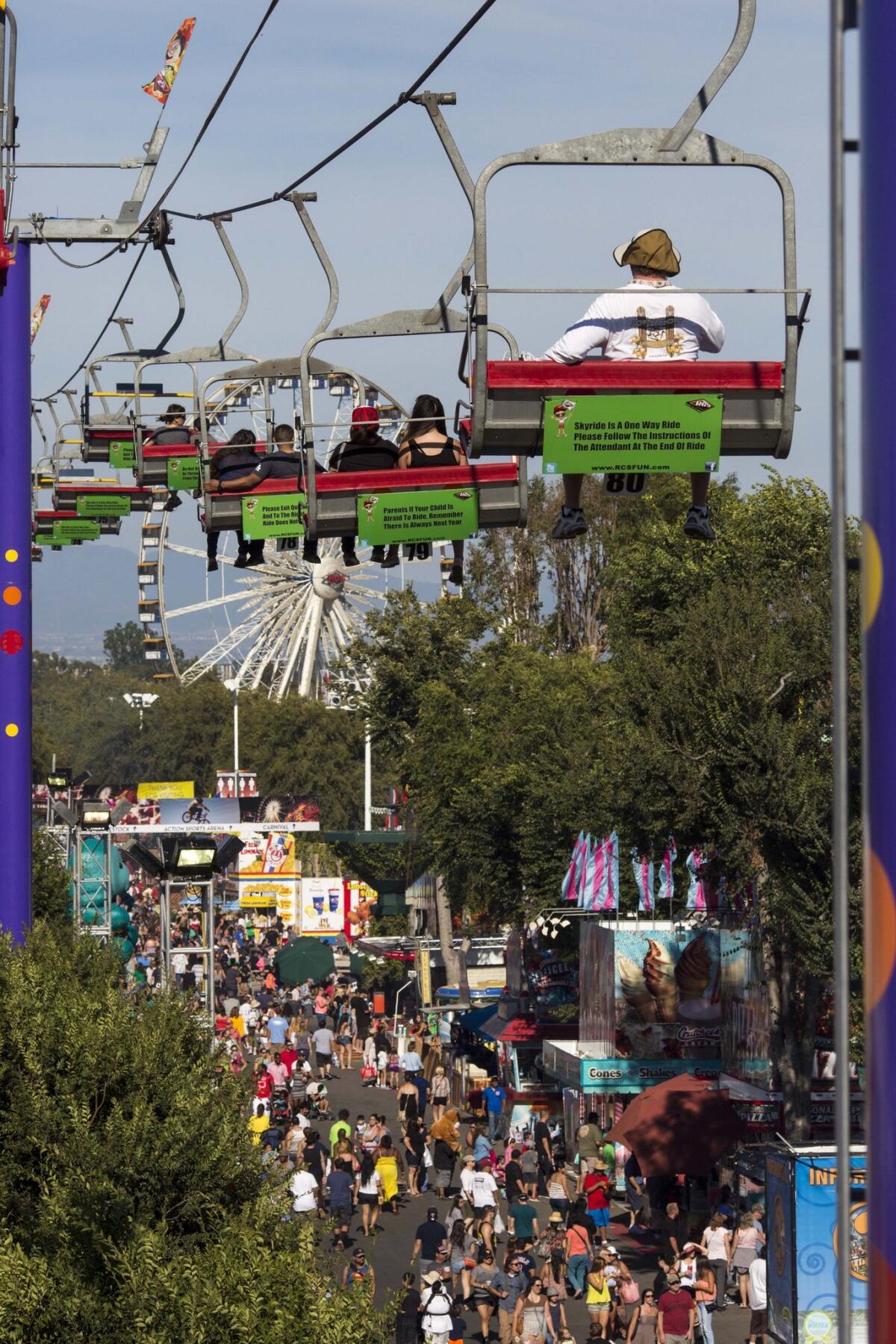 Patrons watch from a ski lift ride as fairgoers enjoy entertainment, rides, games, animals and deep-fried splendor on the first day of the Orange County Fair in 2014. For the 2015 celebration of the fair's 125th anniversary, a series of "pop-up" parties will be held leading up to the fair's opening.