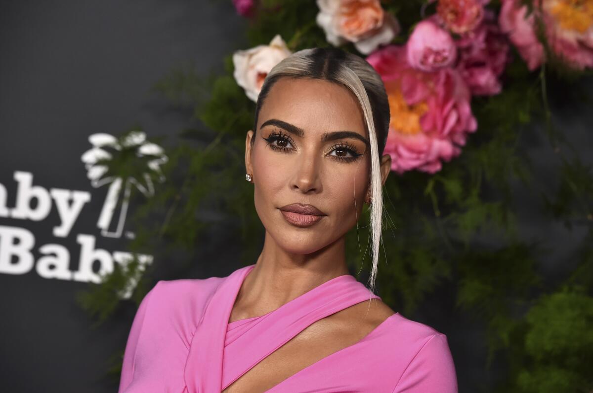 Woman standing on red carpet in pink outfit with dark hair awith blond highlights pulled up